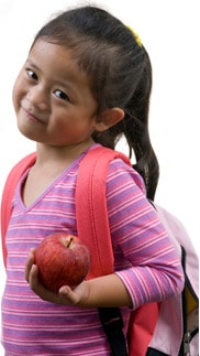 School girl with backpack holding apple